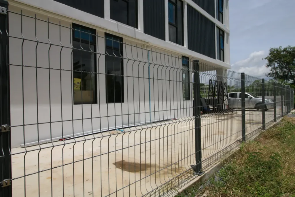 รั้วตะแกรงเหล็กแบบ 3D ล้อมพื้นที่รอบอาคารสำนักงาน โชว์การติดตั้งที่มั่นคงและแนวเสารั้วเป็นระเบียบ