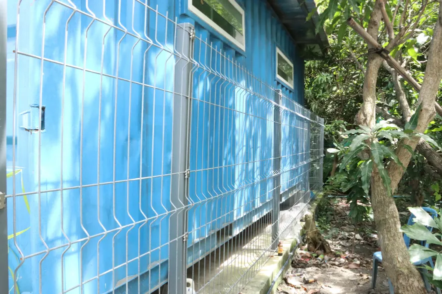 รั้วตะแกรงเหล็กสีเทาแบบ 3D ติดตั้งล้อมบ้านชั้นเดียวในพื้นที่สวน พร้อมเสารั้วและ Spider Fitting ชัดเจน